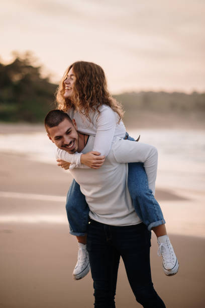 istock Young couple walking piggyback on a beach at sunset 1281105008