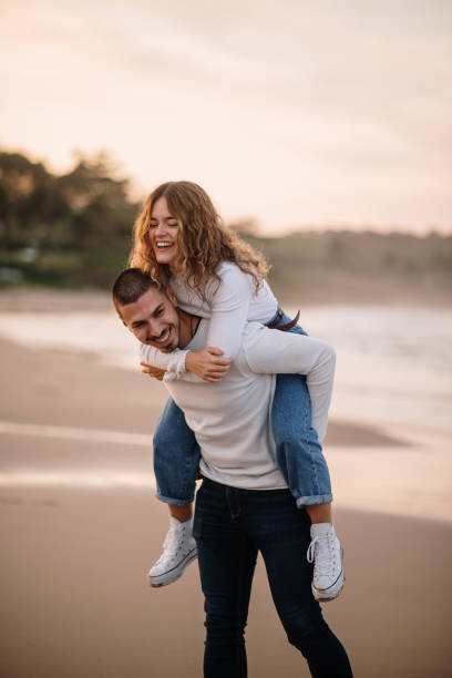 istock Young couple walking piggyback on a beach at sunset 1281105176
