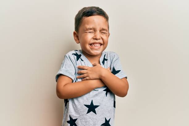 adorável criança latina vestindo roupas casuais sorrindo com as mãos no peito, olhos fechados com gesto grato no rosto. conceito de saúde. - heart shape child human hand childhood - fotografias e filmes do acervo