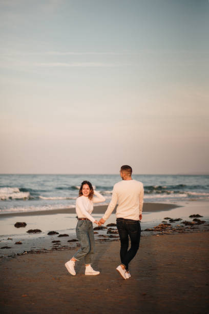 istock Young couple walking at a beach at sunset 1281106547