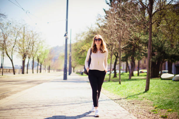 Full lengths shot of elegant middle aged woman wearing sunglasses while walking on the street alone.
