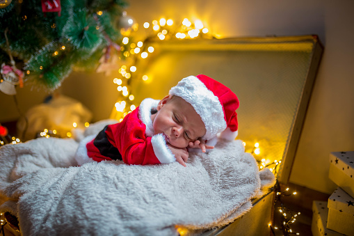 Portrait of newborn baby in Santa clothes and christmas hat, lying on the ground, winter snow landscape outdoor