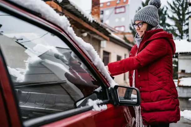 Photo of Woman cleaning snow off her car