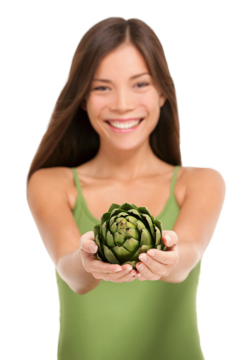 Woman holding fresh artichoke globe flower closeup isolated on white background. Asian happy girl showing green vegetable ingredient for cooking in cupped hands. Artichokes healthy diet concept.