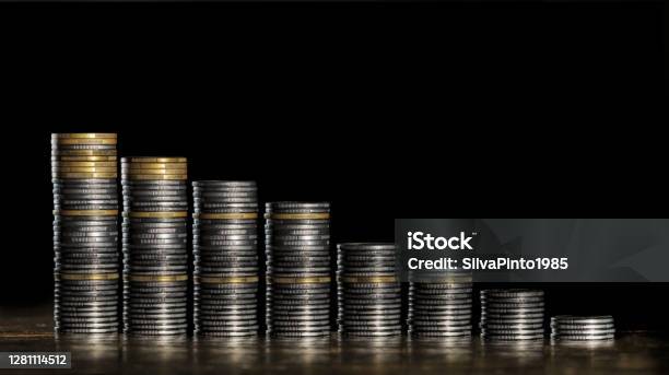 Coin Stacks On A Descending Ladder Image Alluding To The Financial Market Stock Photo - Download Image Now