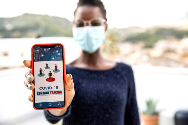 Woman showing mobile phone screen with a contact tracing App Woman showing mobile phone screen with a contact tracing App, to trace positive contacts during pandemic time. tracing stock pictures, royalty-free photos & images