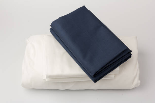 istock Stack of clean white and blue bed sheets on white  background, closeup. 1281115616