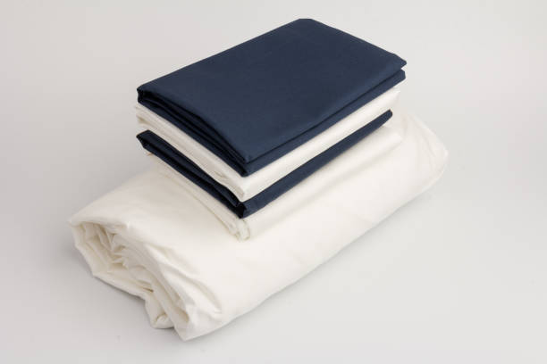 istock Stack of clean white and blue bed sheets on white  background, closeup. 1281115644