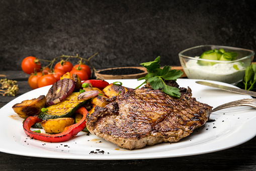 Sliced grilled medium rare Top sirloin beef steak on a plate. Dark background. Top view.