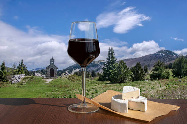 copa de vino tinto con queso brie contra paisaje del valle de montaña con capilla de piedra. - italian chapel fotografías e imágenes de stock