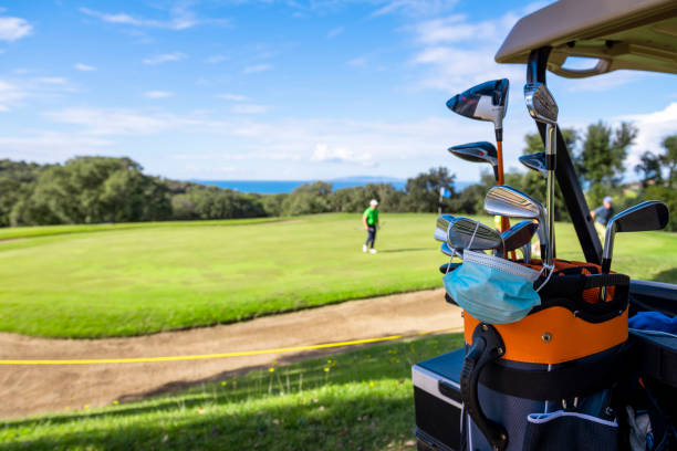 maske zum schutz vor viren, infektionen, epidemien, auf golfschlägern platziert. - golf golf course swinging isolated stock-fotos und bilder