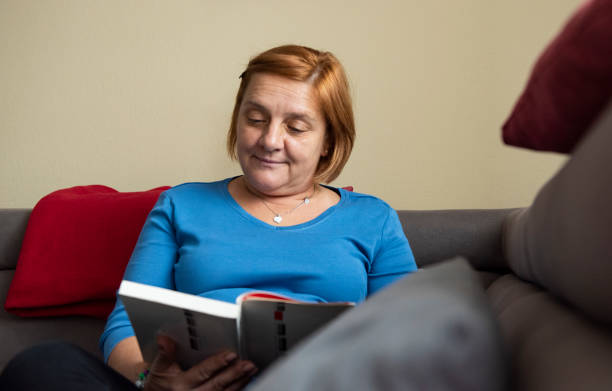 istock Mature woman with book at home 1281120793