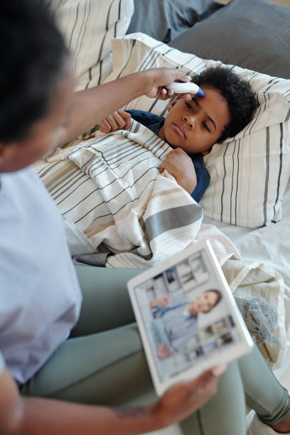 istock Sick little boy lying under blanket and having his body temperature measured 1281124562