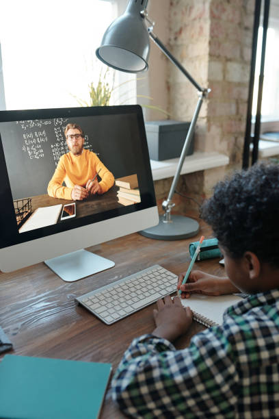 istock Little schoolboy listening to his teacher on computer screen and making notes 1281124653
