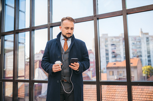 A business man listens to music and drinks coffee