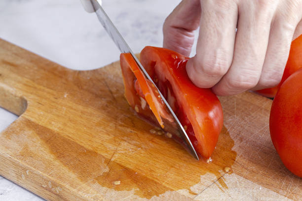 istock Woman's hands cutting fresh tomato slices 1281126174