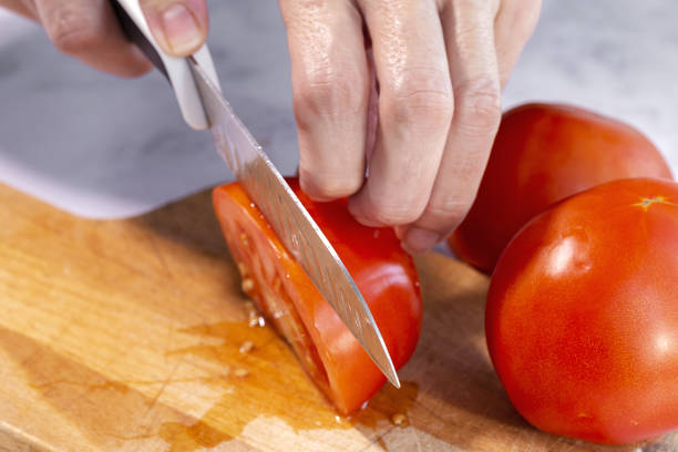 istock Woman's hands cutting fresh tomato slices 1281126175