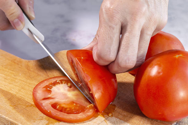 istock Woman's hands cutting fresh tomato slices 1281126184
