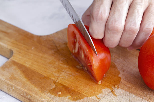 istock Woman's hands cutting fresh tomato slices 1281126221