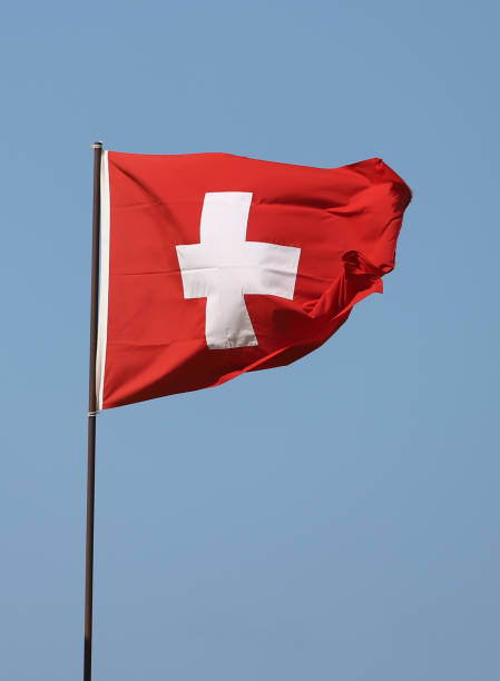 istock Swiss flag flying on flagpole on blue sky background 1281127066