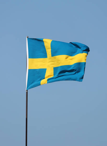istock Swedish flag flying on flagpole on blue sky background 1281127145
