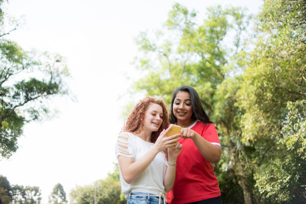 istock Two young girls in the park using cellphone. 1281127358