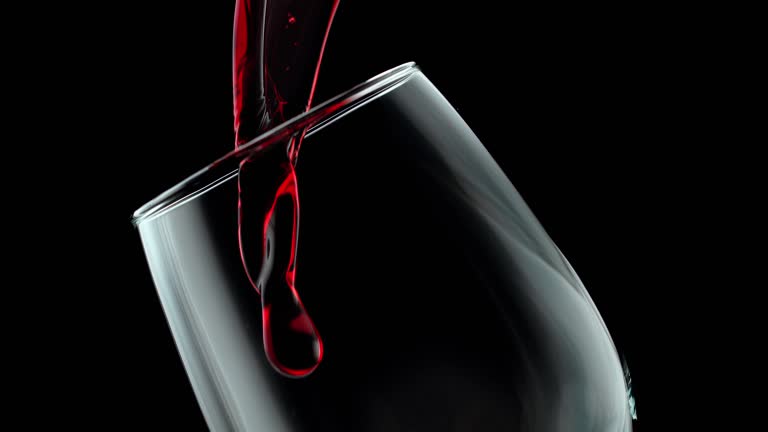 Pouring Red Wine into a Glass on the Black Background in Slow Motion