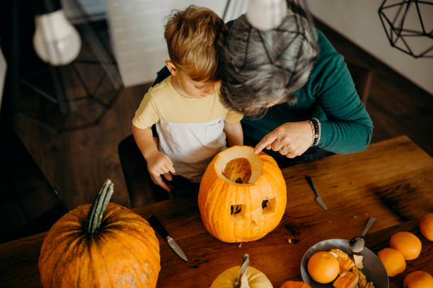 istock Grandma helps her grandson cut pumpkin 1281128679