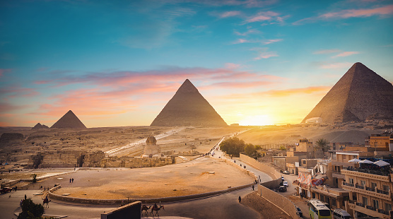 Pyramids of Giza, Giza Necropolis, Egypt - October 29, 2022: Man sitting on a camel in front of the Pyramids of Giza and the Great Sphinx of Giza.\n\nThe Giza Necropolis is a large area near Giza, a suburb of Cairo that has many tombs and burial sites. It is also where you can find the famous Pyramids of Giza, the Great Sphinx, and more. The name comes from the ancient Greek word nekropolis, which literally means “city of the dead”.\n\nThe Giza Complex was once near the ancient Egyptian capital of Memphis, and the Giza plateau is where a number of pharaohs, queens, and nobles of the Fourth Dynasty of ancient Egypt were buried. \n\nAll three of Giza's pyramids and their elaborate burial complexes were built  from roughly 2550 to 2490 B.C. The pyramids were built by Pharaohs Khufu, Khafre, and Menkaure.