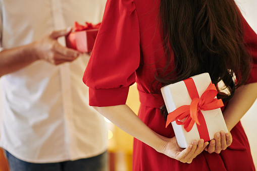 Young woman hiding present for boyfriend behind her back