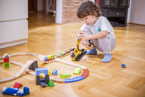 istock Beautiful little boy playing with a railroad train toy and plastic vehicle. 1281136242