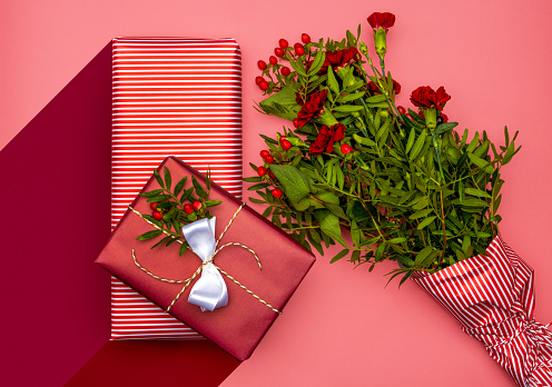 Flowers and Presents wrapped in paper ready to be given away. Gifts on red and pink background