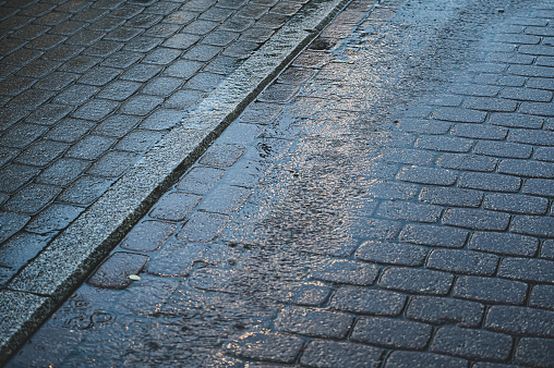 Nested gray paving stones with puddles in the evening rain. Wet stones.