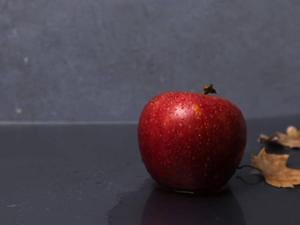 istock Red apple in a puddle of rain with drops 1281146210