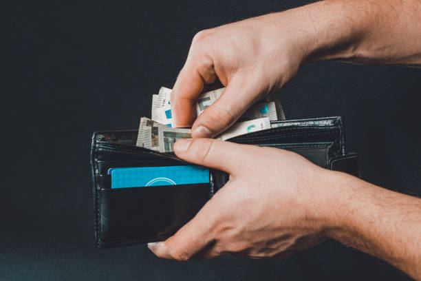 istock Man hand pulling money from wallet, black background and black wallet. 1281146470