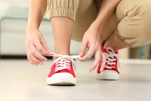 Front view of woman tying shoelaces of sneakers