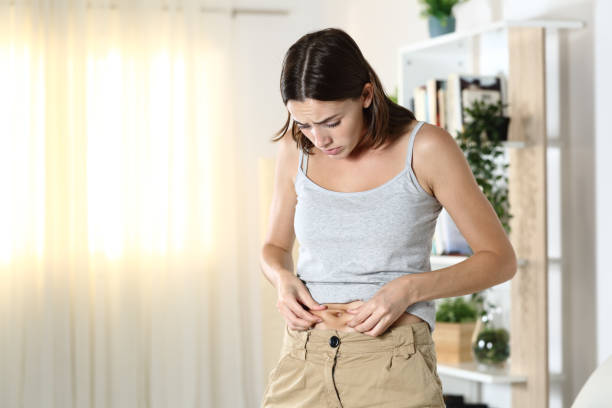 mulher preocupada com a gordura corporal tocando sua barriga - aparência - fotografias e filmes do acervo