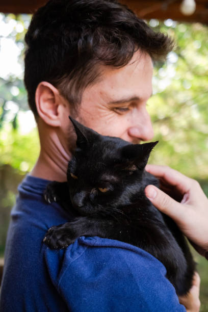 istock Man petting a black cat on his shoulder 1281153877