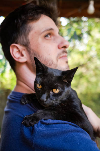 istock Man holding a cute black cat on his shoulder 1281153914