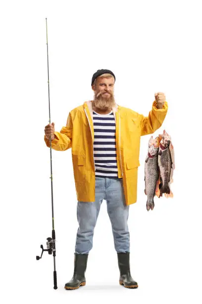 Full length portrait of a fisherman in a yellow rain coat holding a fishing pole and fish isolated on white background