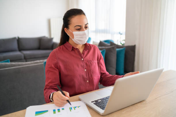 istock The business woman wearing a protective face mask makes statements using the graphics in front of her at the business meeting she attends with her laptop from home 1281154968