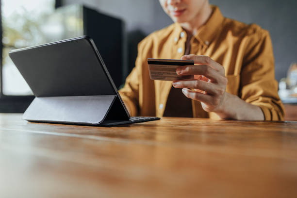 istock Man Using a Credit Card to Shop Online on his Digital Tablet 1281156905