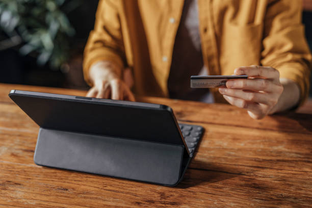 istock Man Using a Credit Card to Shop Online on his Digital Tablet 1281156909