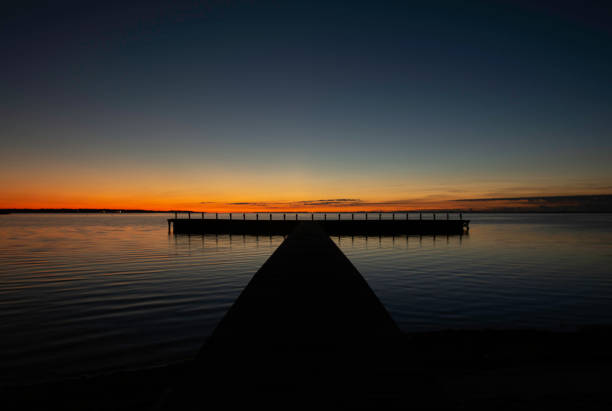 light from sunset shining through beams of covered boat dock on Lake Guntersville, Alabama with silhouette of mountains in background