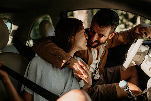 A beautiful couple enjoying their stops in nature, ready to go to net destination. But first, the girl is leaning toward her handsome partner, kissing him while hugging, before the road.