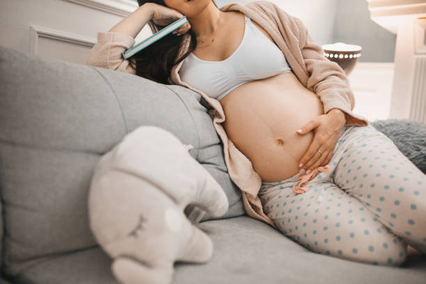 istock Pregnant woman reading book in on the sofa 1281166152