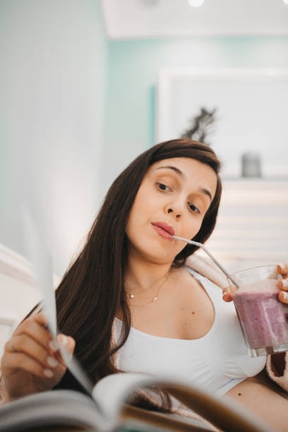 istock Pregnant woman reading book and drinking smoothie 1281166436