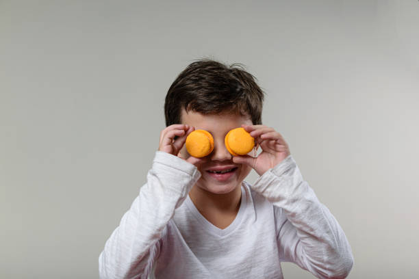 istock 6 year old child, smiling and putting 2 macaroons in his eyes. 1281168355
