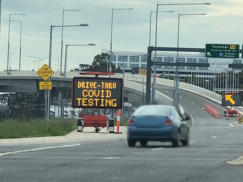 A sign showing the set up of drive through Covid testing at an airport location