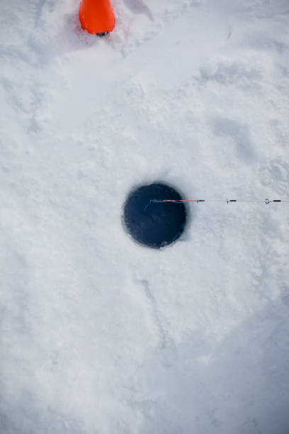An ice fishing hole on a local lake being used by a fisherman